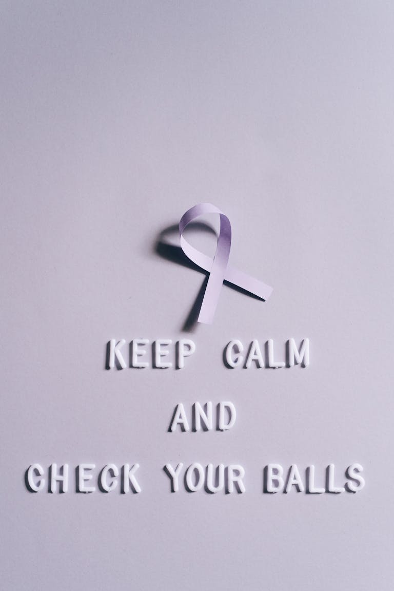 Light pink ribbon on a light background with quote for testicular cancer awareness.